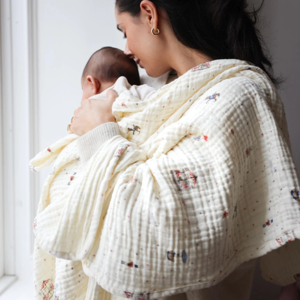 Sfeerbeeld van moeder met baby gewikkeld in Cam Cam Copenhagen hydrofiele babydeken 100x100 cm met Carousel print